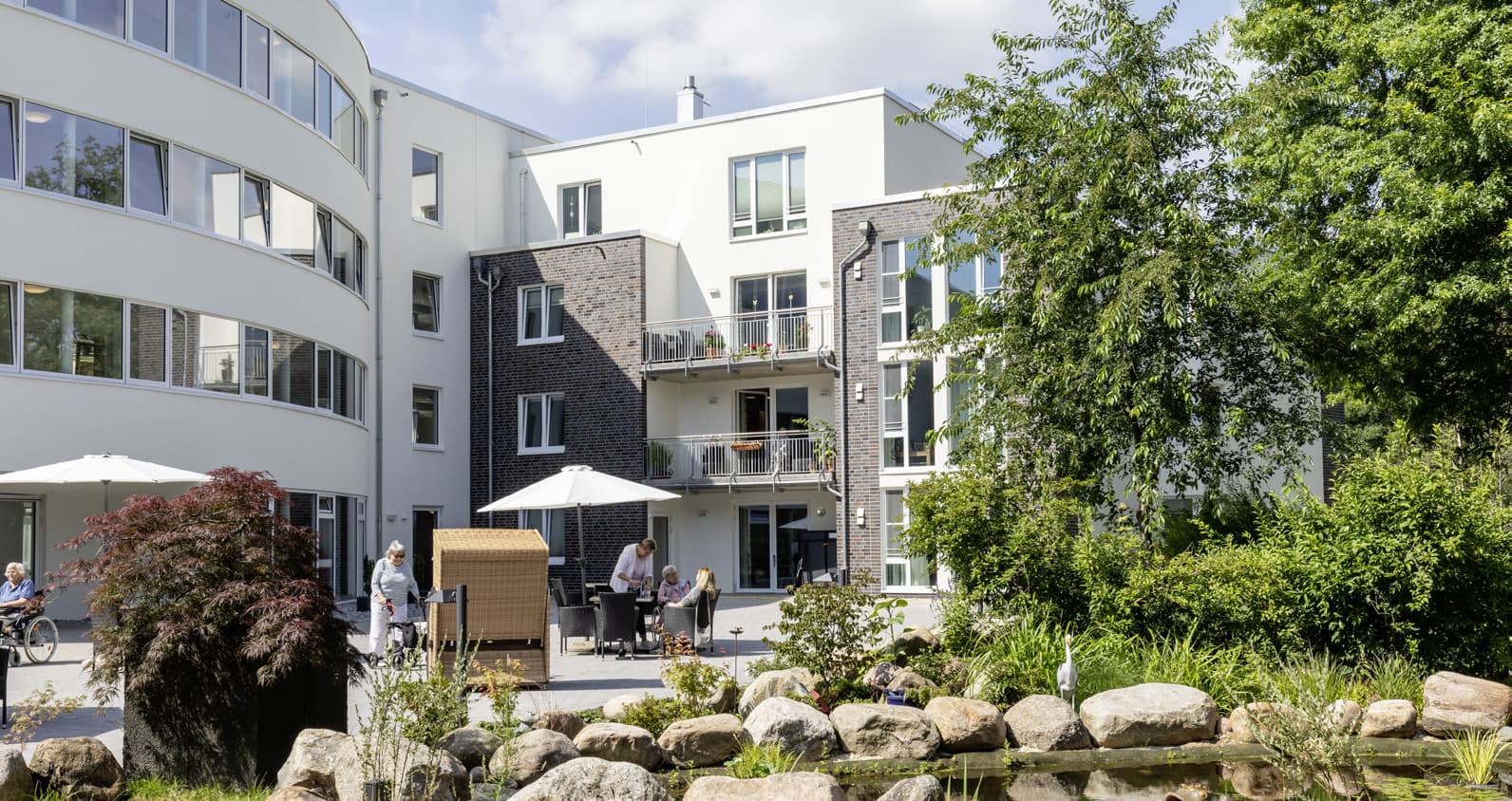 Innenhof mit Teich, Sonnenschirmen und Wohngebäuden