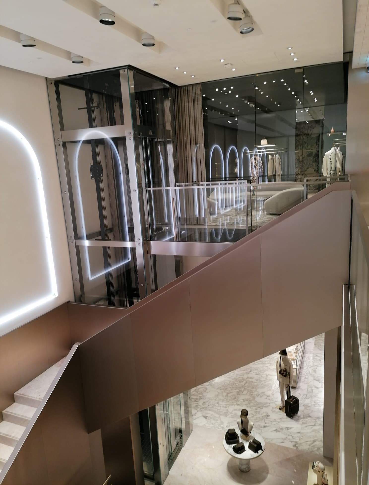 Treppe und Glasaufzug mit beleuchteten Bögen